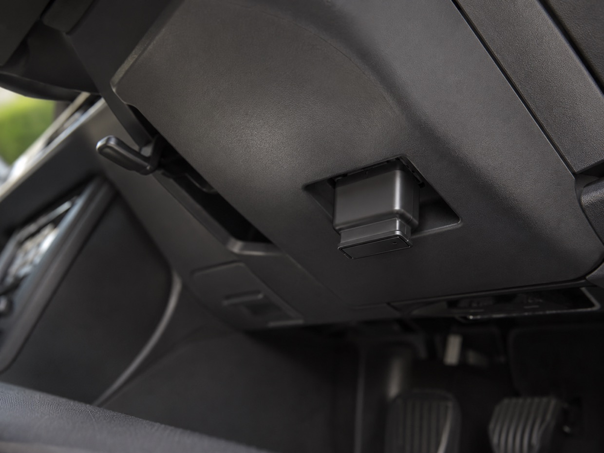 A Bluetooth OBD reader plugged into the diagnostic port under a car's dash